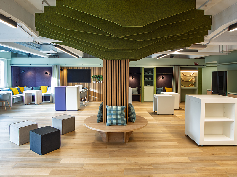 Innenarchitektur von Atelier Türke, modern gestalteter Arbeits- und Aufenthaltsbereich mit zentralem stilisiertem Baum aus Holzpanellen und Filz.