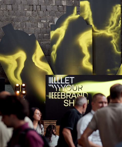 Inszenierter Messebereich bei der Hausmesse von Atelier Türke mit großformatigen, grafischen Elemente in kontrastreicher Farbwelt, leuchtender Markenbotschaft und Menschen im Vordergrund. Eine atmosphärische Markeninszenierung im Ausstellungsdesign mit starker visueller Wirkung.