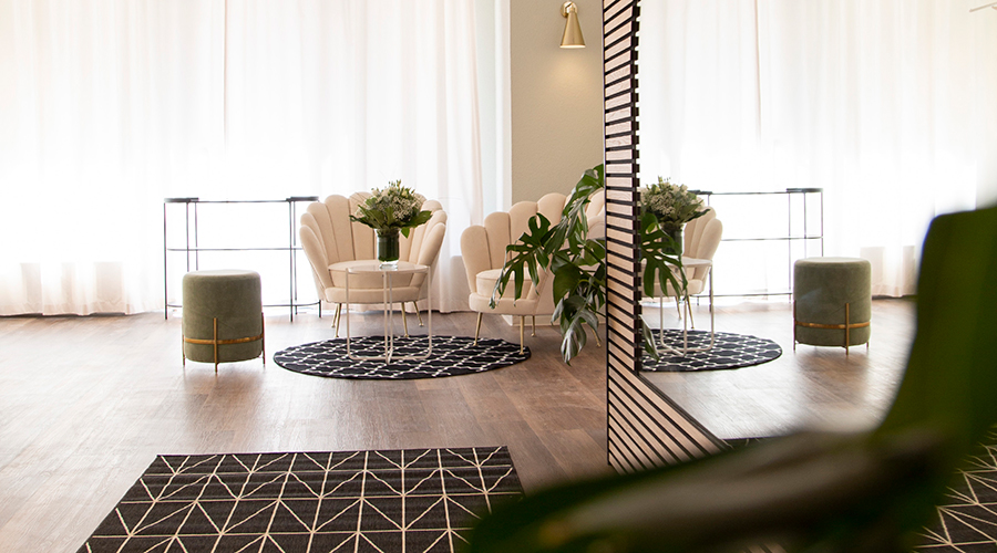 Heller Loungebereich von Kenny S mit eleganten Sesseln, Pflanzen, Teppichen und einem großen Spiegel. Ruhiges, modernes Raumkonzept mit wohnlicher Atmosphäre. Raumgestaltung für das Unternehmen von Atelier Türke.