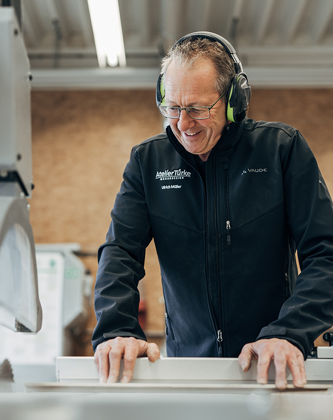 Ulrich Müller, Mitarbeiter im Lager bei Atelier Türke, konzentriert an der Werkbank im Zuschnitt